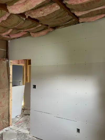 Basement under construction with hung drywall, exposed insulation, and framed doorway.