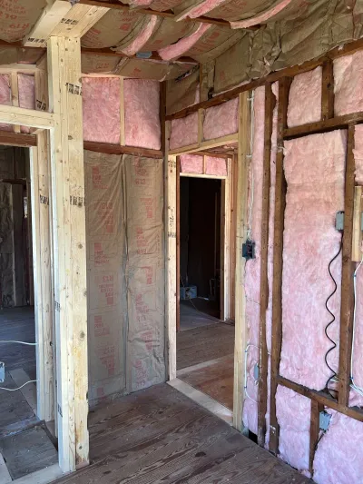 Unfinished interior with exposed wood framing, pink fiberglass insulation, and rough-in electrical wiring.