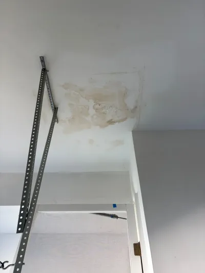 Ceiling corner with visible water staining above a closet doorway, indicating a leak needing repair.