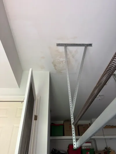 Garage ceiling with a brown water stain around a metal support bracket near a torsion spring.
